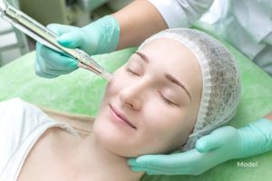 Woman receiving a microneedling treatment while smiling.