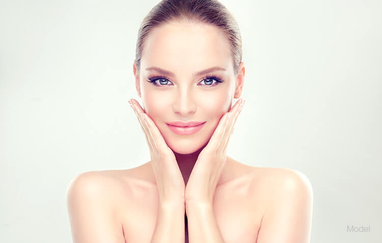 Woman resting her hands under her chin with youthful skin.
