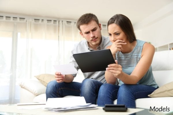 Couple doing research online with concerned facial expressions.