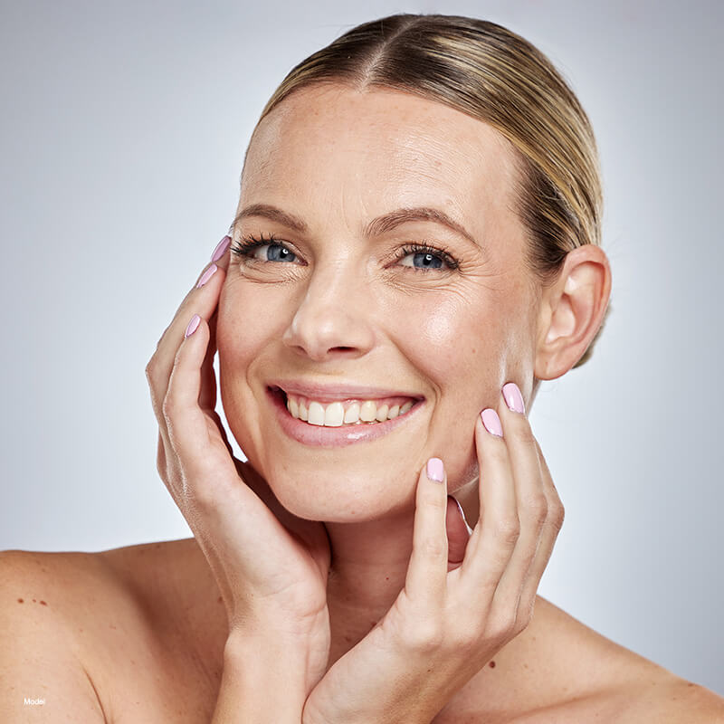 Woman smiling and touching her face