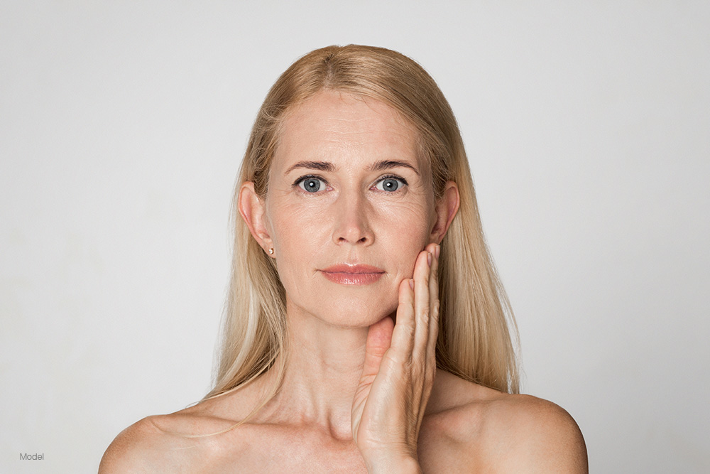 Mature blonde woman touching her face